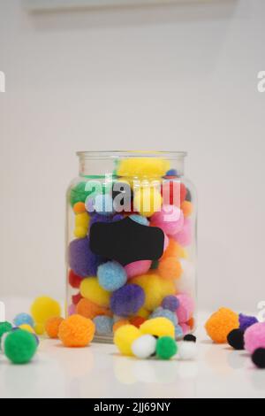 Colourful pom pom on a jar with background space for text. Background for art and crafts uses. Stock Photo