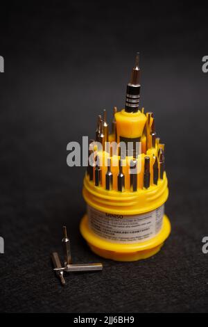 yellow multifunctional set of small screwdrivers on a black background. Stock Photo
