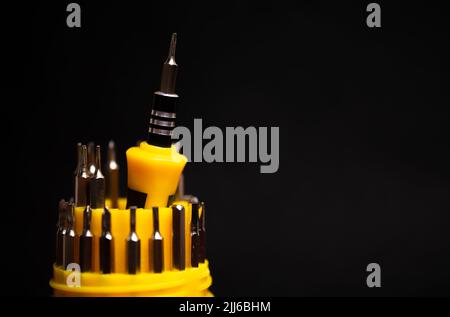 yellow multifunctional set of small screwdrivers on a black background. Stock Photo