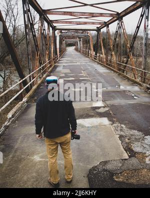 A vertical shot of a male photographer on an old broken bridge Stock Photo