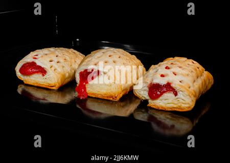 Three homemade buns with red strawberry jam baking in electric oven Stock Photo