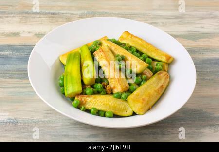 Vegetable dish of zucchini squash and green peas in white bowl Stock Photo