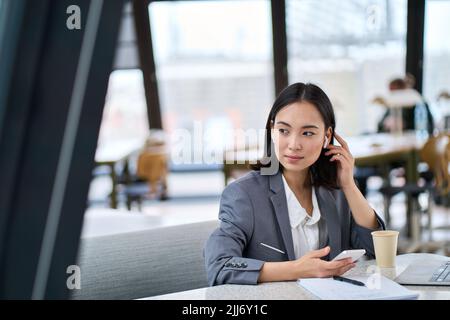 Young Asian business woman using smartphone working in modern office. Stock Photo
