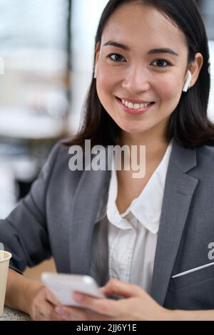 Young smiling Asian business woman wearing suit using phone. Portrait Stock Photo