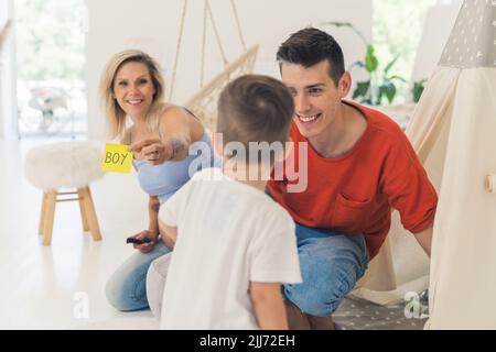 Young parents surprise their toddler boy with a gender reveal of their second child. Healthy relationships concept. Family growing. High quality photo Stock Photo