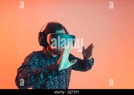 Stylish young man in a shirt and with virtual reality goggles on his head is playinh the arcade vr game - studio. High quality photo Stock Photo