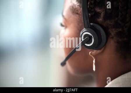 We listen well so we can respond effectively. Rearview shot of a young call centre agent working in an office. Stock Photo