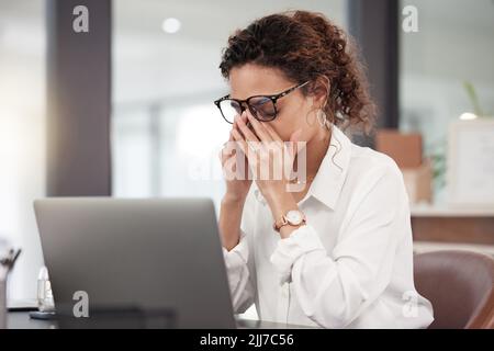Im really giving it my all. a young businesswoman looking stressed while sitting at her desk. Stock Photo