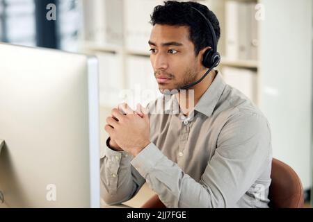 Whats serious to you is serious to him. a young businessman using a headset and computer in a modern office. Stock Photo