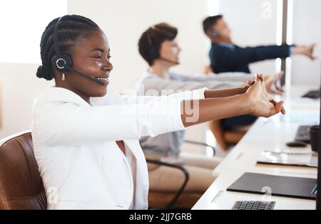 Im ready to make those big sales. a young call centre agent stretching her arms while working in an office. Stock Photo