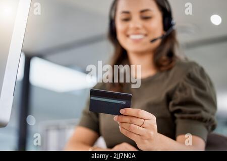 Ill quickly collect your info. a young female call center agent holding a credit card at work. Stock Photo