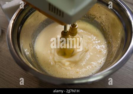 Beating with electric mixer sugar and eggs in a bowl Stock Photo