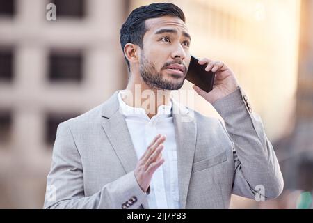 Can I go ahead with the deal. a handsome young businessman standing in the city and using his cellphone. Stock Photo