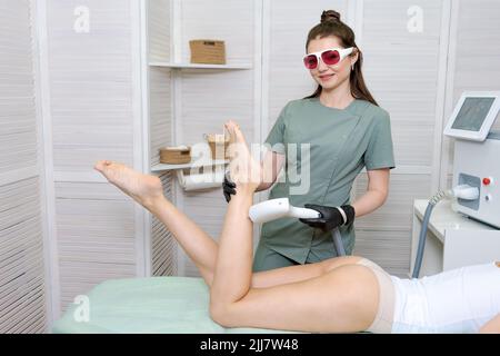 Laser hair removal and cosmetology in a beauty salon. Hair removal procedure. Laser hair removal, cosmetology, spa and hair removal concept. Beautiful young caucasian woman on procedure Stock Photo