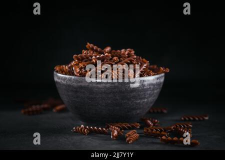 Organic uncooked Buckwheat Fusilli pasta on a dark background. Wholegrain gluten free noodles. Healthy food concept. Stock Photo