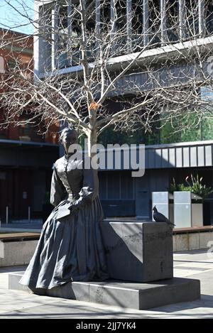 Sculpture of Catholic saint Mary MacKillop, sitting with book in hand next to a pigeon, outside ACU's Melbourne campus Stock Photo