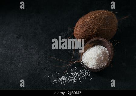 Whole coconut with coconuts flakes on a black background Stock Photo