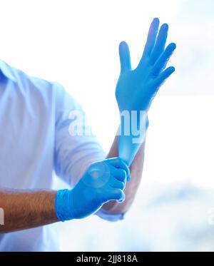 Get those gloves on and get to work. an unrecognisable dentist putting on rubber gloves. Stock Photo