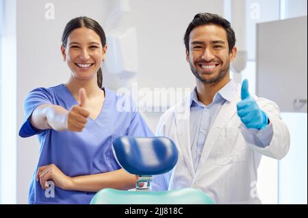 Well get your teeth looking good. Portrait of two young dentists showing thumbs up in their consulting room. Stock Photo