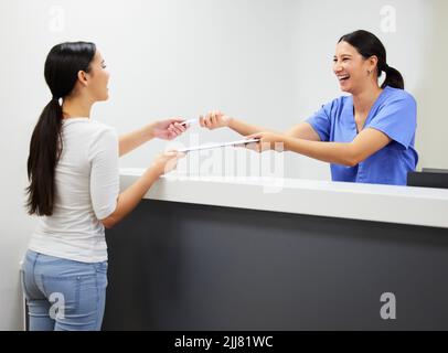 oure never fully dressed without a smile. a patient and assistant interacting in a dentist office. Stock Photo