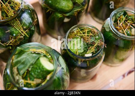 Preservations, conservation. Salted, pickled marinated cucumbers with herbs, dill and garlic in a jar on an rustic wooden crate. Canning food for the Stock Photo