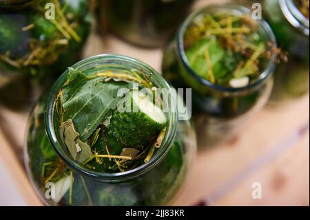 Autumn pickling and canning of vegetables. Close-up of glass jars with homemade canned cucumbers on a wooden surface. Healthy organic fermented food c Stock Photo