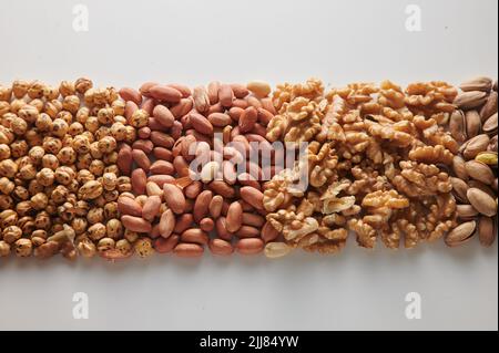 Top view pile of hazelnuts with unpeeled peanuts placed on clear white background with walnuts and pistachios in light studio Stock Photo