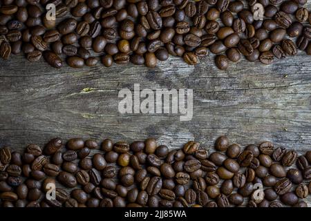 picture of coffee beans stacked on wooden floor on a dark background with copy space Stock Photo