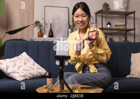 Chinese Female Blogger Making Video On Cellphone Making Makeup Indoors Stock Photo