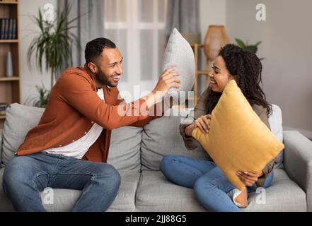 Joyful African Couple Having Pillow Fight For Fun At Home Stock Photo