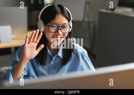 Korean Businesswoman Video Calling On Computer Waving Hello In Office Stock Photo