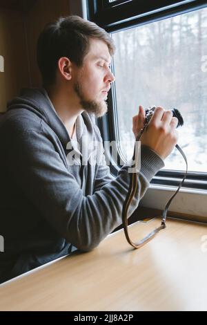 man sits at a table in a train with a camera Stock Photo