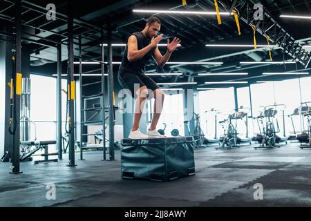 Motivated black male athlete doing balance exercise on cube in modern gym Stock Photo
