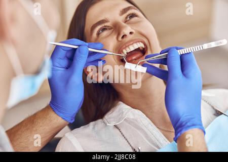 Professional male doctor is doing anestetic injection to happy female patient in stamotology cabinet Stock Photo