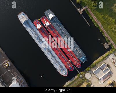 Petrochemical energy heavy transport industry cargo vessel tankers top down aerial drone view. Docked bulk carrier ship along storage facility silos Stock Photo