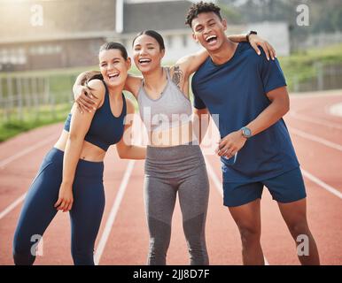 Having a blast out on the track. three young athletes standing outside together on the track. Stock Photo