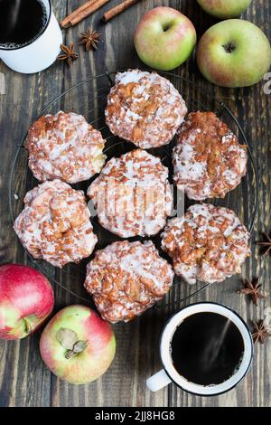 Flatlay of glazed apple fritters and fresh black coffee with fresh apples, cinnamon bark and anise. Top view. Stock Photo
