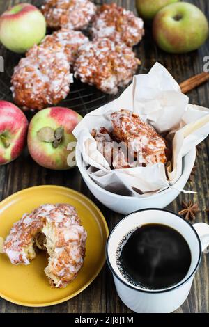 Glazed apple fritters and fresh hot steaming black coffee with fresh apples, cinnamon bark and anise. Top view. Stock Photo