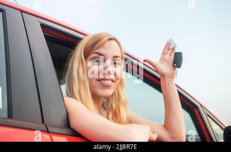 Car driver woman smiling showing new car keys and car. Stock Photo