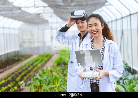 Researcher using drone controller with fly view glasses monitor plant growing in Agriculture farm. Stock Photo