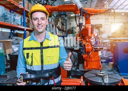 Portrait smart engineer man working with advance robotic machine weling in heavy industry. Stock Photo