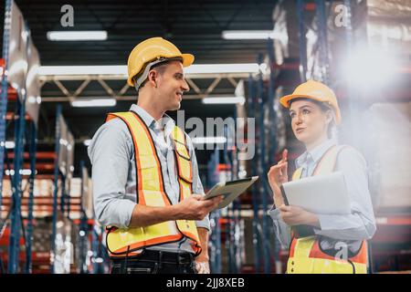 Caucasian male staff worker in cargo warehouse manager talking work with lady teamworking industry. Stock Photo