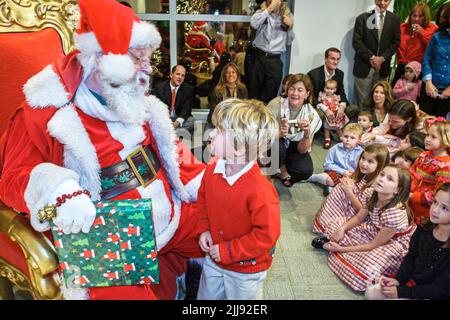 Miami Florida,office Christmas party Santa Claus child children boy boys girl girls,present parents group people person scene in a photo,USA US Stock Photo