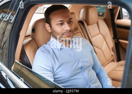 Pensive young man seated in luxury car Stock Photo