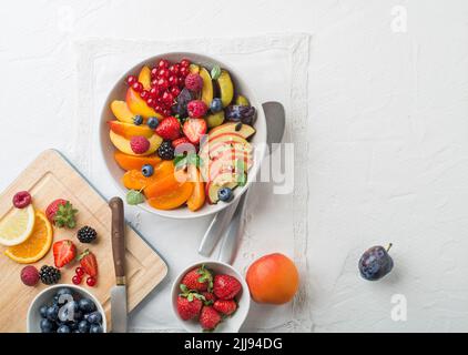 Preparing of healthy fresh fruit salad on white table background Stock Photo