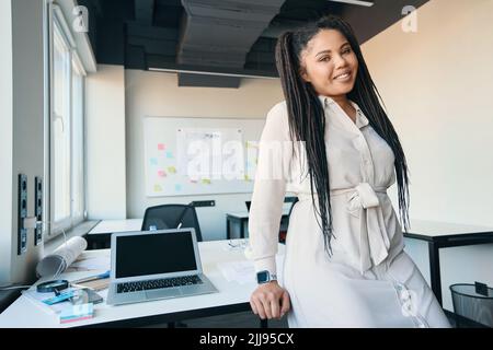 Joyous modern businesswoman posing for camera in her workplace Stock Photo