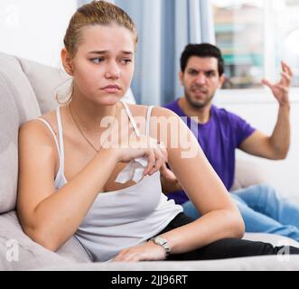 Stressed woman on couch with disgruntled husband Stock Photo
