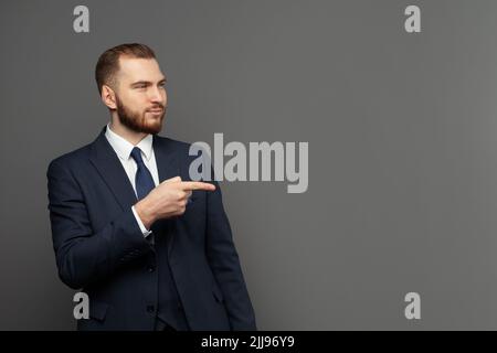 Portrait of cheerful excited joyful satisfied handsome attractive businessman dressed in formal outfit pointing on empty blank copy space isolated on Stock Photo