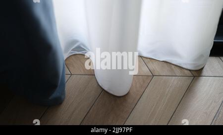 Beautiful white curtains indoors and wooden parquet floor closeup Stock Photo