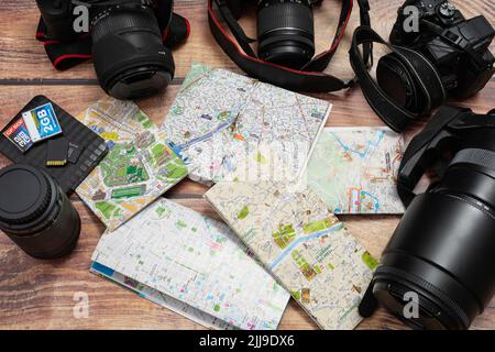 City maps next to cameras and passport on a wooden table. Concept of vacations, travels, travelers, Copy space. Stock Photo